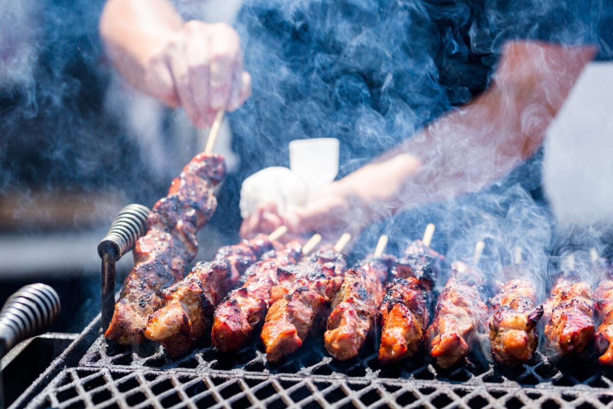 Meat smoking over a BBQ grill on a sunny day.