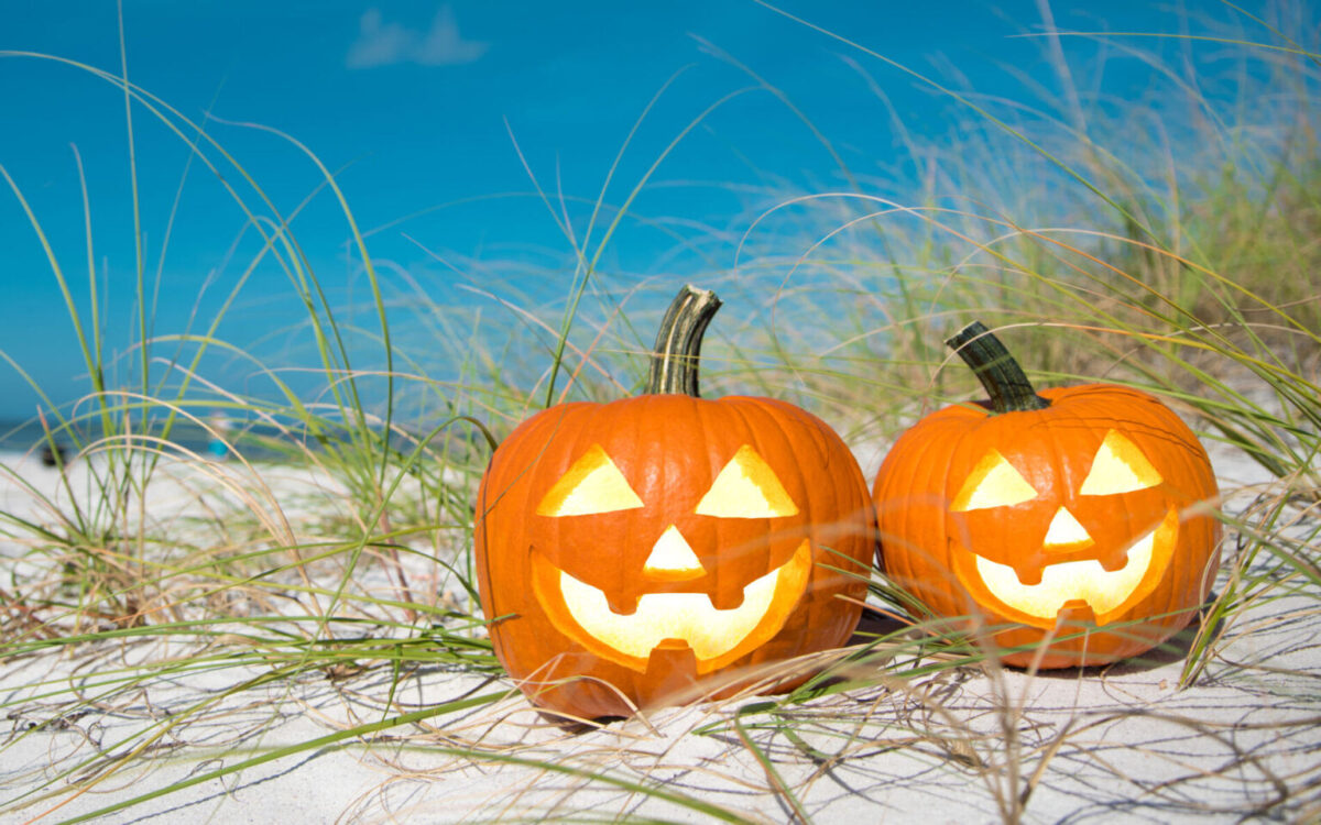 Jack-o-lanterns sitting in the sand on a beach
