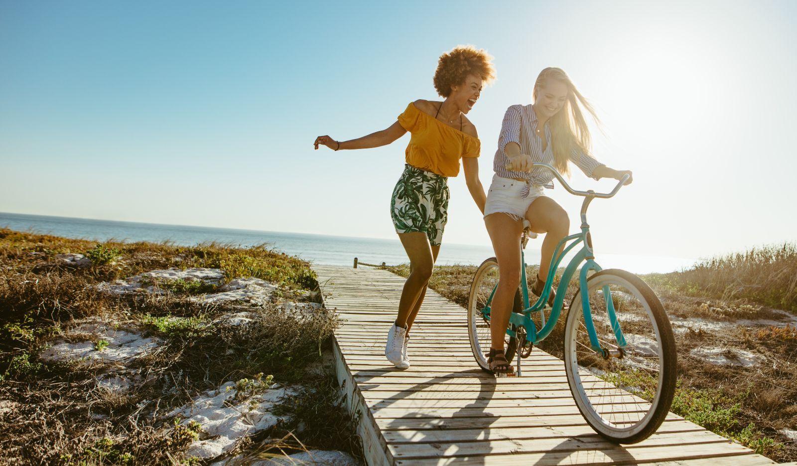 two women playing with bike on beach