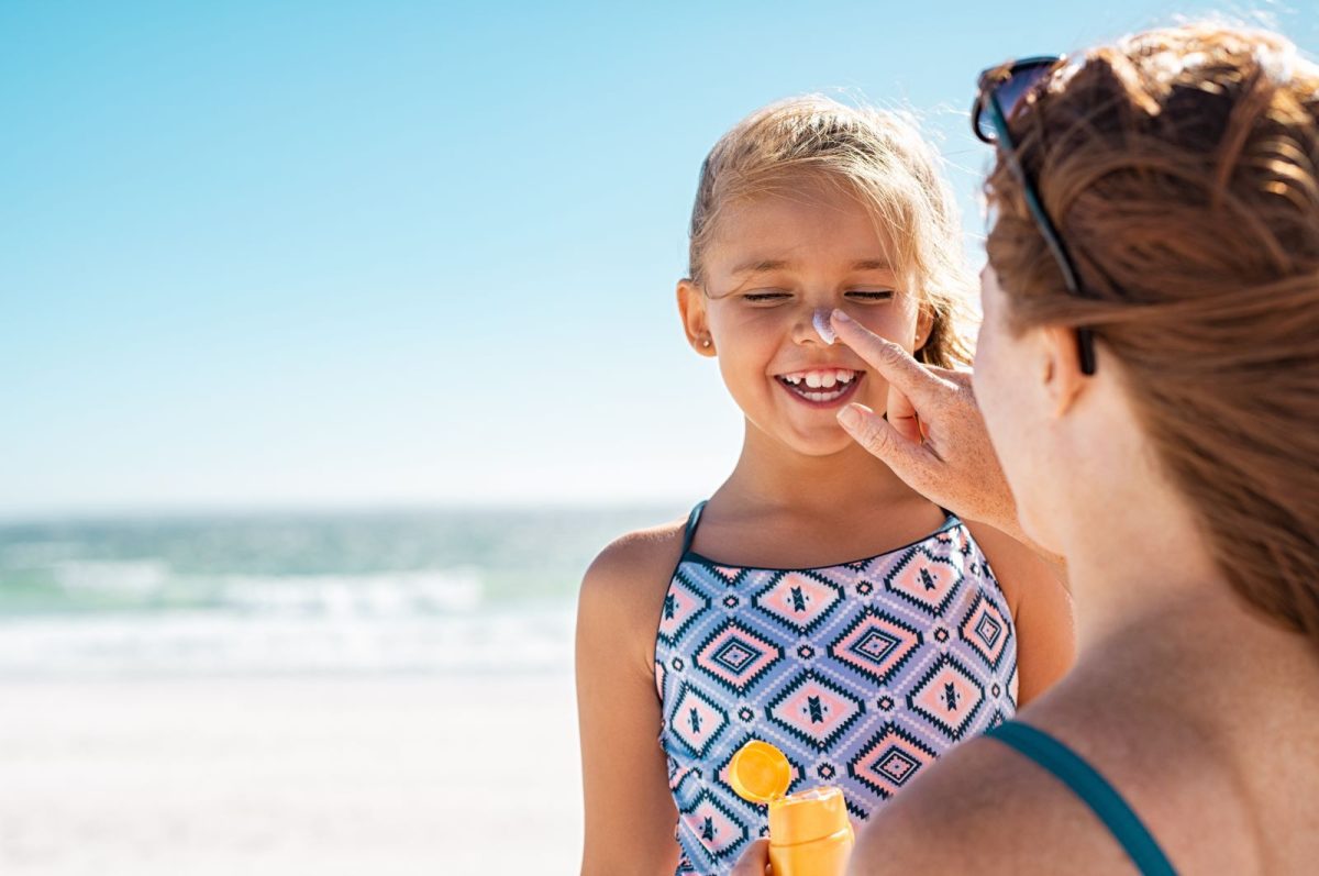 mother placing sunscreen on her daughter's nose 